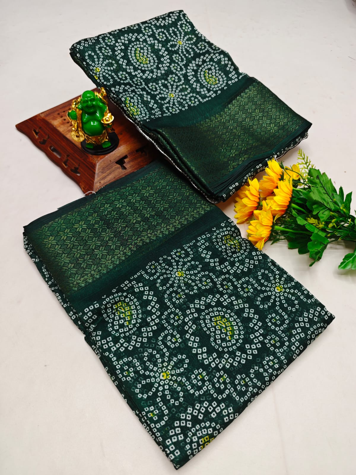 Green patterned fabric with a wooden box and flowers on a white background