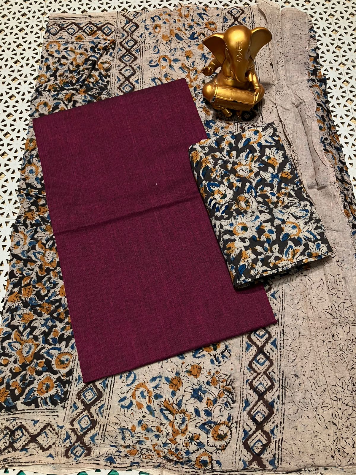 Purple fabric on a patterned fabric background with a gold decorative item.