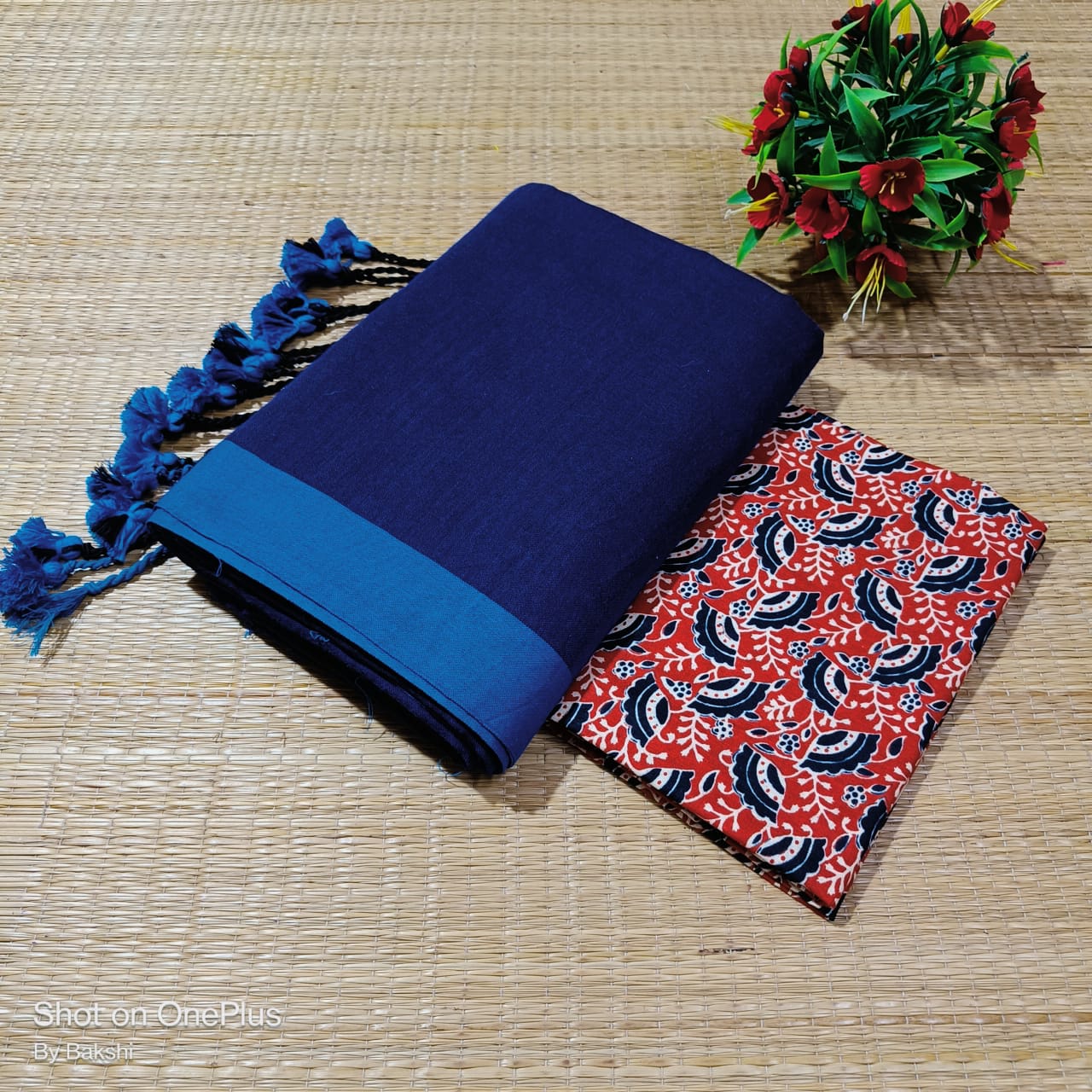 Blue fabric with tassels and a red and blue patterned fabric on a woven surface.